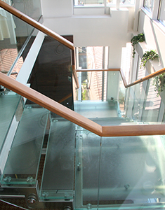 Лестница со стеклянными ступенями и ограждениями с профильными деревянными поручнями